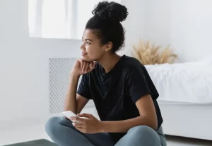 Young african american woman holding her cell phone looking into the distance